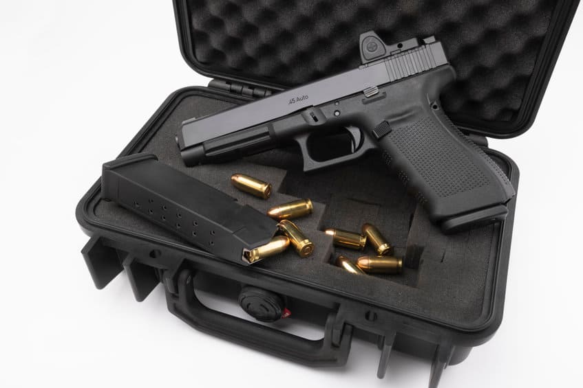 Automatic gun and bullets in a plastic hard case on white backgr